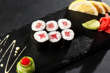 Maki Sushi Rolls with tuna on black stone on dark background. Sushi menu. Japanese food. Closeup of delicious japanese food with sushi roll. Horizontal photo