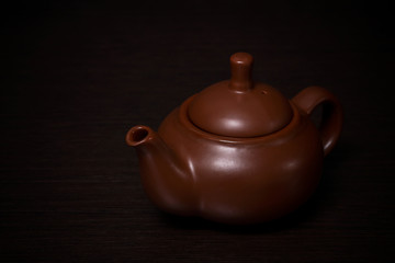 Clay teapot on a dark wooden table.