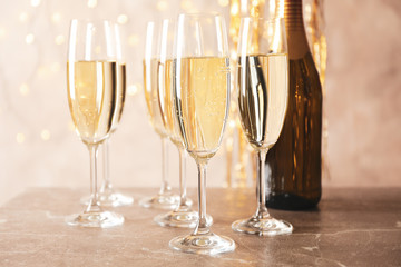 Champagne glasses and bottle against blurred lights background, close up