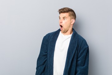 Young caucasian man wearing pajama being shocked because of something she has seen.