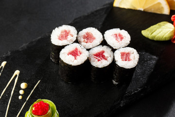 Maki Sushi Rolls with tuna on black stone on dark background. Sushi menu. Japanese food. Closeup of delicious japanese food with sushi roll. Horizontal photo