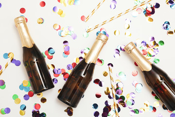 Composition with mini champagne bottles and glitter on white background, top view