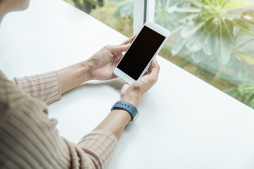 Close-up view of woman hands holding smartphone on white table. Using Technology Concept.