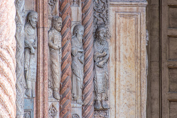 Statues carved on stone wall of medieval building in Italy
