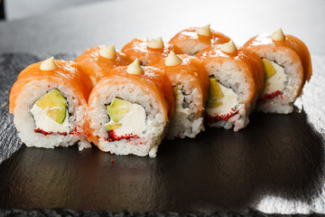 Sushi Rolls with salmon, avocado, flying fish caviar and Cream Cheese inside on black slate isolated. Philadelphia roll sushi with salmon. Sushi menu. Horizontal photo.