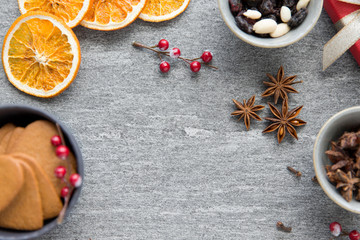 Fototapeta premium christmas, winter holidays and seasonal drinks concept - hot mulled wine, dry orange slices, raisins with pine cones and aromatic spices on grey background