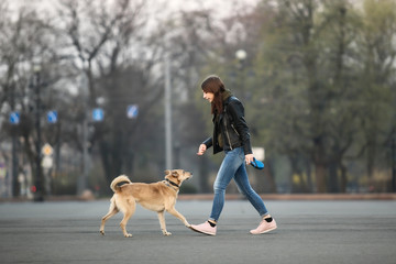 Woman having fun with dog on square during sunrise