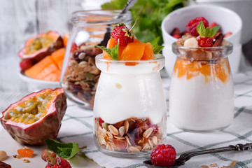 Natural yogurt, granola and mashed passion fruit and mango layered in a glass jar. Breakfast idea