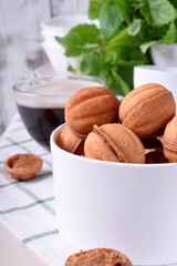 Walnut shaped cookies with condensed milk in a round box and a cup of coffee