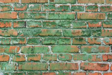 Beautiful horizontal texture of part of an old orange crushed brick wall colored in green