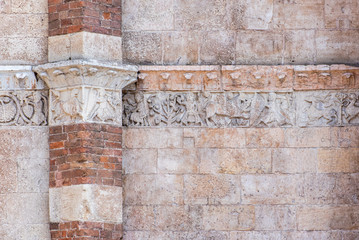 Detail of scene carved on exterior wall of medieval building in Italy