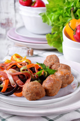 Multicolored pasta and meatballs garnished with parsley served on the white ceramic plate