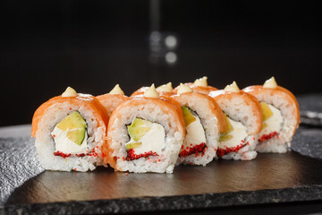 Sushi Rolls with salmon, avocado, flying fish caviar and Cream Cheese inside on black slate isolated. Philadelphia roll sushi with salmon. Sushi menu. Horizontal photo.