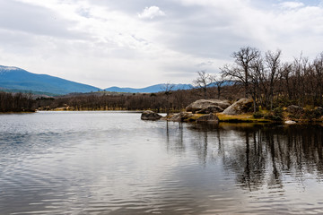 Obraz premium Scenic view of lake and reflections on the water against mountains. Ponton Alto reservoir in Segovia.