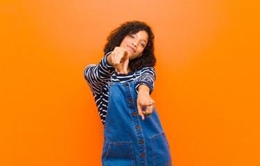 young pretty black woman feeling happy and confident, pointing to camera with both hands and...