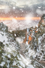 Stunning Winter sunset landscape from mountains looking over snow covered countryside in heavy snow storm