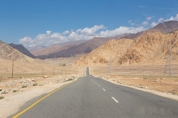 Long straight asphalt road leading to big high mountain