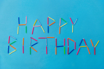 holiday, celebration and party concept - words happy birthday made of colorful candles on blue background