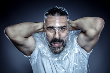 portrait of a man with a beard and his face wrapped in a plastic film.