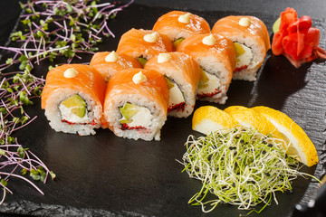 Sushi Rolls with salmon, avocado, flying fish caviar and Cream Cheese inside on black slate isolated. Philadelphia roll sushi with salmon. Sushi menu. Horizontal photo.
