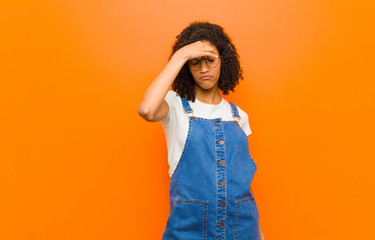 young pretty black woman feeling stressed, unhappy and frustrated, touching forehead and suffering...