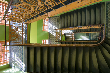 Old rounded staircase with railing, green walls, big windows. Top view 1