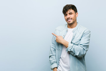 Young hispanic cool man smiling and pointing aside, showing something at blank space.