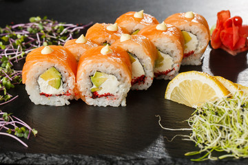 Sushi Rolls with salmon, avocado, flying fish caviar and Cream Cheese inside on black slate isolated. Philadelphia roll sushi with salmon. Sushi menu. Horizontal photo.