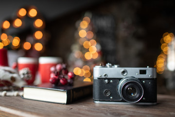 Retro camera is on the table on the background of Christmas songs and Christmas trees