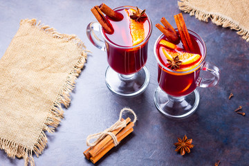 Red mulled wine on burlap. Mulled wine with oranges, cinnamon and cloves on a dark background. Hot...