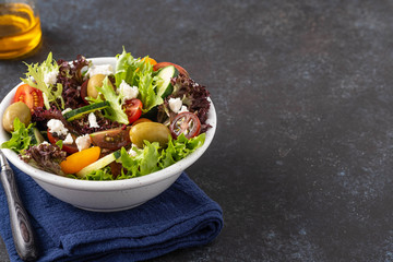 Salad of cucumbers, tomatoes, olives and fresh herbs with olive oil and pepper.