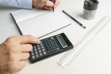 Young man makes calculations on a calculator, accountant, side view