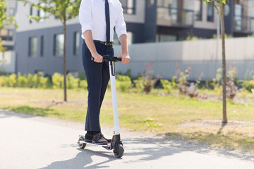 business and people and concept - young businessman riding electric scooter outdoors