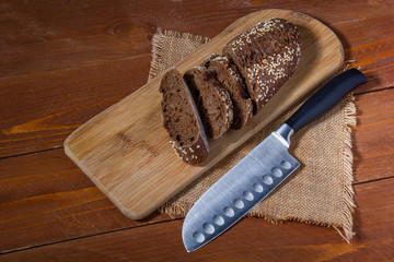 Pieces of black bread on a wooden board, metal knife
