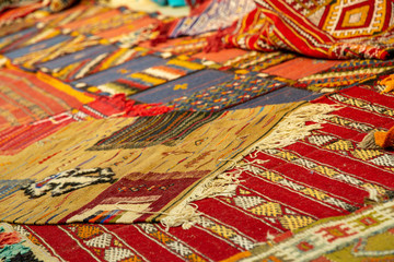 assortment of Moroccan carpets resting on the ground in a souk