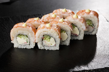 Sushi Rolls with cucumber, shrimp, cram meat and Cream Cheese inside on black slate isolated. Philadelphia roll sushi with shrimp. Sushi menu. Horizontal photo.