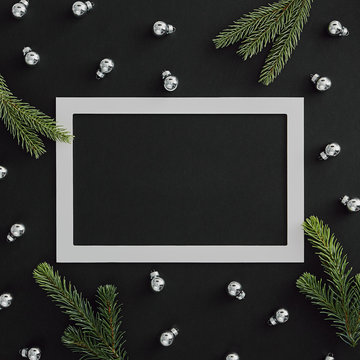 Silver bauble and evergreen tree branch on dark background