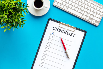 Checklist and pen on blue office background top view