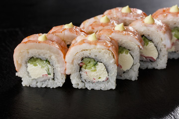Sushi Rolls with cucumber, shrimp, crab meat and Cream Cheese inside on black slate isolated. Philadelphia roll sushi with shrimp. Sushi menu. Horizontal photo.