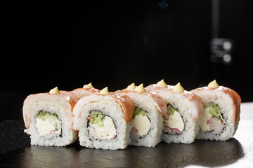 Sushi Rolls with cucumber, shrimp, crab meat and Cream Cheese inside on black slate isolated. Philadelphia roll sushi with shrimp. Sushi menu. Horizontal photo.