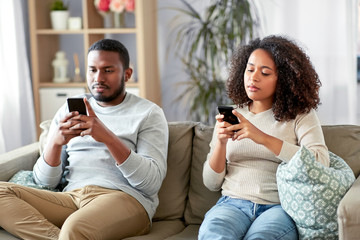 technology, internet and people concept - african american couple with smartphone at home