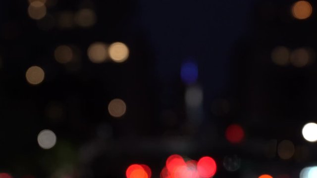 Colorful bokeh of nighttime city traffic lights, frontal driving shot defocused