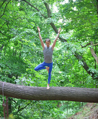caucasian male in tree pose - yoga asana on tree trunk
