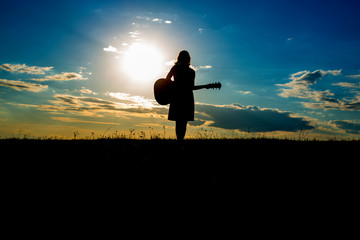 Silhouette woman playing guitar in sunset