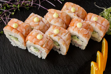 Sushi Rolls with cucumber, shrimp, crab meat and Cream Cheese inside on black slate isolated. Philadelphia roll sushi with shrimp. Sushi menu. Horizontal photo.