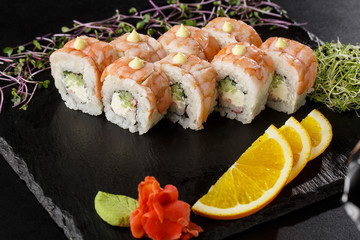 Sushi Rolls with cucumber, shrimp, crab meat and Cream Cheese inside on black slate isolated. Philadelphia roll sushi with shrimp. Sushi menu. Horizontal photo.