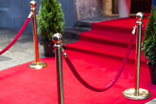 Red carpet at an exclusive event. Award ceremony red carpet and golden stanchions. Festive event or celebrity entrance concept.