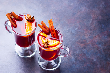 Hot mulled wine with spices on dark background. Christmas mulled wine with orange, star anise and...