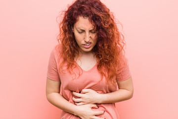 Young natural and authentic redhead woman sick, suffering from stomachache, painful disease concept.