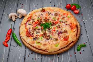 Traditional italian pizza with minced meat on wooden background